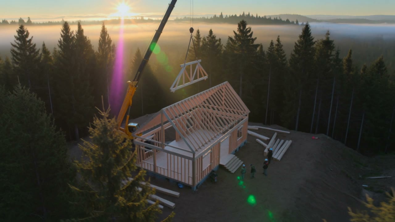 Structure de bois en cours d'érection, une ferme de toit hissée par une grue