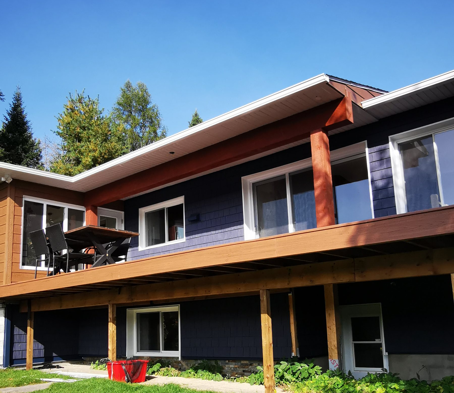 Façade arrière d'une résidence avec revêtement de bardeau marine et grande terrasse